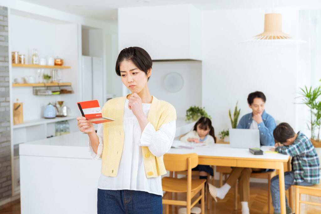 ダイニングルームで通帳を持つ主婦