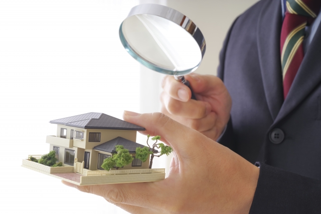 家の模型と虫眼鏡で査定する人