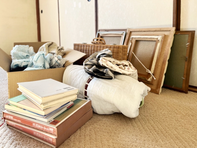 段ボール箱に入れた衣類と本といくつかの額縁