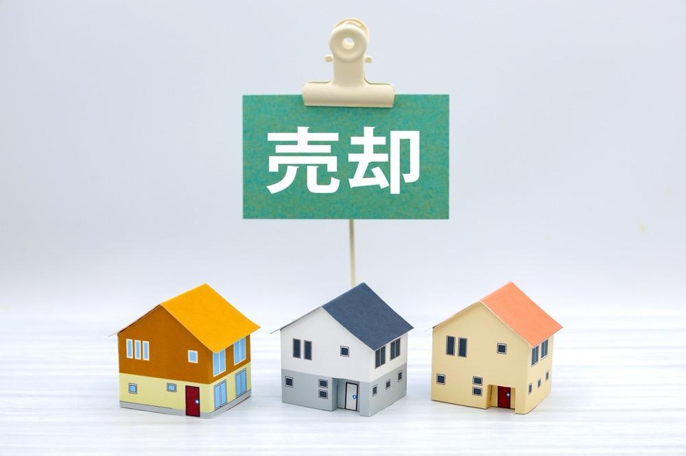 売却中を告知するミニチュア住宅と立て札