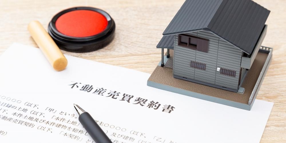 不動産売買契約書と印鑑、住宅模型